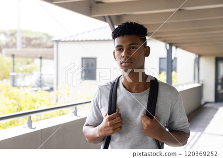 Standing outside school building, teenage boy with backpack looking thoughtful Standing outside school building, teenage boy with backpack looking thoughtful 120369252