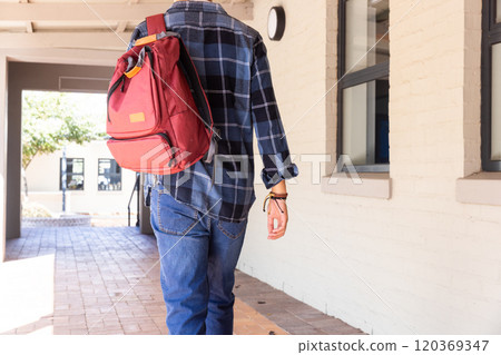 Walking in school hallway, asian teenage boy with red backpack wearing plaid shirt Walking in school hallway, asian teenage boy with red backpack wearing plaid shirt 120369347