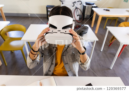 Using VR headset, asian teenage boy exploring virtual reality in school classroom Using VR headset, asian teenage boy exploring virtual reality in school classroom 120369377