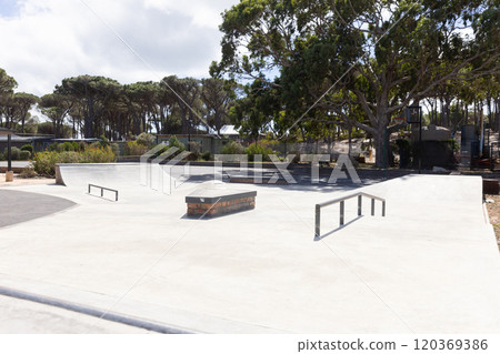 Outdoors, Empty skate park with ramps and rails surrounded by trees and greenery 120369386