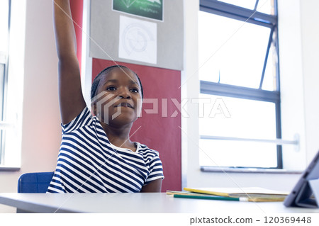 In school, african american girl raising hand in classroom, eager to answer question In school, african american girl raising hand in classroom, eager to answer question 120369448