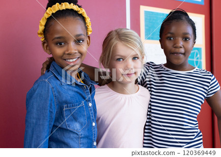 Standing together and smiling, multiracial schoolgirls posing for photo in classroom Standing together and smiling, multiracial schoolgirls posing for photo in classroom 120369449
