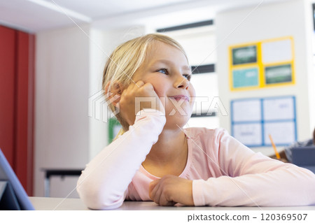 In school, girl daydreaming at desk, looking away with thoughtful expression 120369507