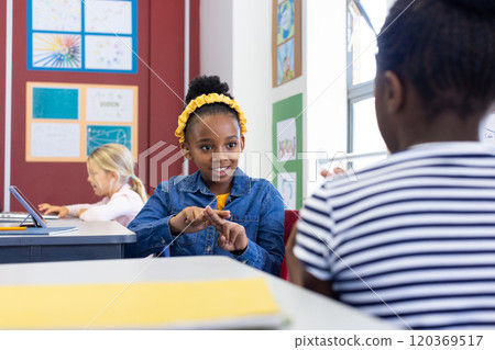 In school, african american girl using sign language to communicate with classmate in classroom 120369517