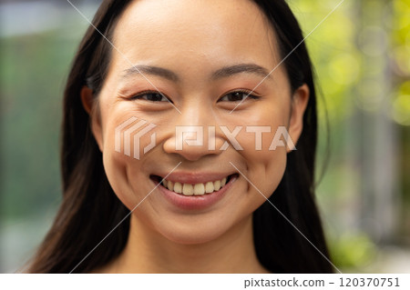 Smiling asian woman with long hair, close-up portrait outdoors in natural light 120370751