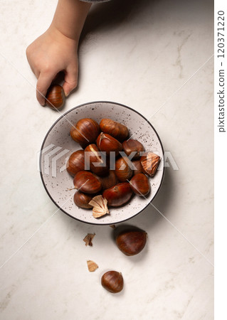A child puts edible chestnuts in a bowl 120371220