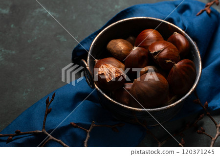 A bowl with edible chestnuts stands on a blue cloth A bowl with edible chestnuts stands on a blue cloth 120371245
