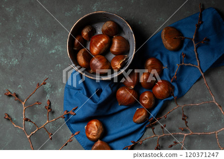 A bowl with edible chestnuts stands on a blue cloth A bowl with edible chestnuts stands on a blue cloth 120371247