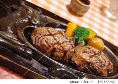 Charcoal-grilled hamburger steak served on a hot iron plate 120372890