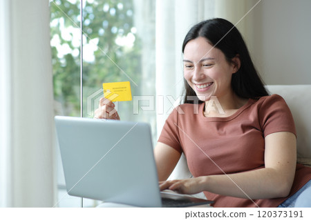 Happy asian woman buying online with credit card Happy asian woman buying online with credit card 120373191