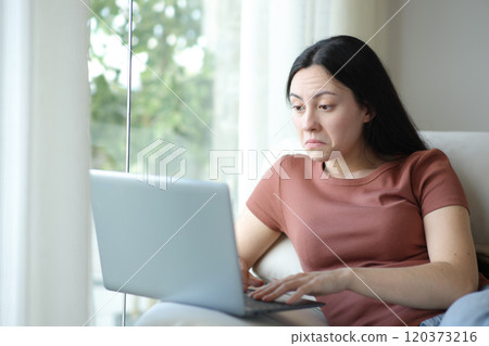 Perplexed asian woman using laptop at home Perplexed asian woman using laptop at home 120373216