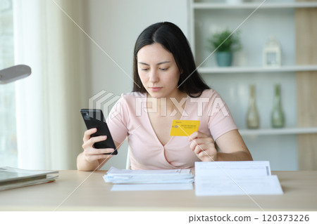 Serious asian woman paying invoices online at home Serious asian woman paying invoices online at home 120373226