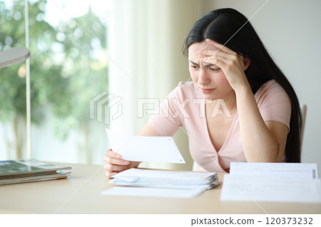 Worried asian woman checking invoice at home 120373232