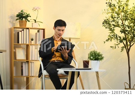 Asian businessman in suit using a digital tablet in stylish workspace 120373411