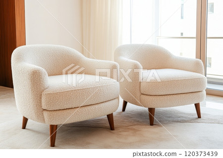Two stylish boucle chairs invite relaxation in a light-filled modern room, enhancing the contemporary decor 120373439