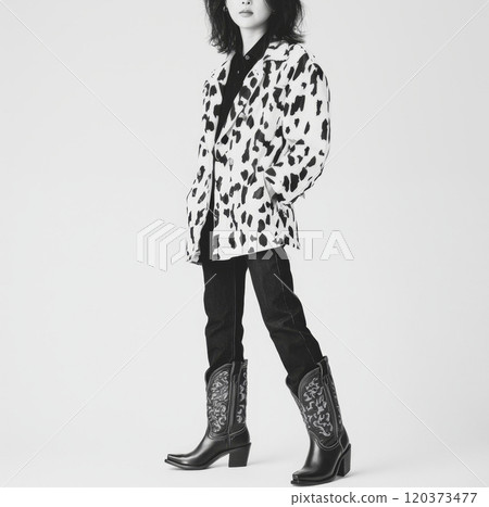 A girl wearing a cow print jacket and cowboy boots poses confidently, embodying a trendy western-inspired style 120373477