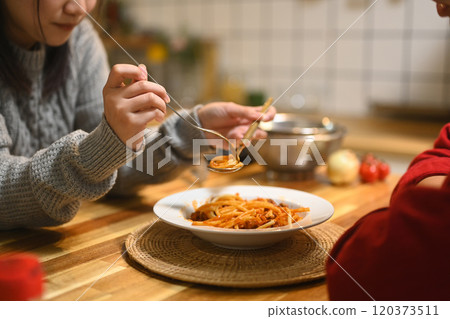 Young woman savoring delicious plate of pasta in a warm kitchen. People, food and holidays concept Young woman savoring delicious plate of pasta in a warm kitchen. People, food and holidays concept 120373511
