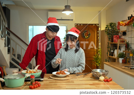 Happy young couple tasting a delicious homemade pasta dish in a kitchen Happy young couple tasting a delicious homemade pasta dish in a kitchen 120373532