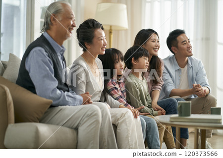 three generation asian family watching tv together at home three generation asian family watching tv together at home 120373566
