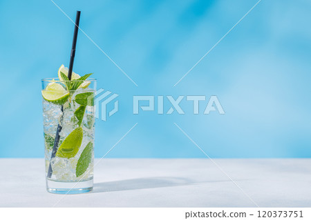 A mojito cocktail arranged on a table against a light blue background 120373751