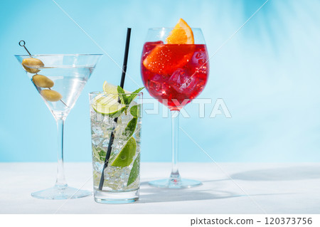A variety of cocktails arranged on a table against a light blue background 120373756