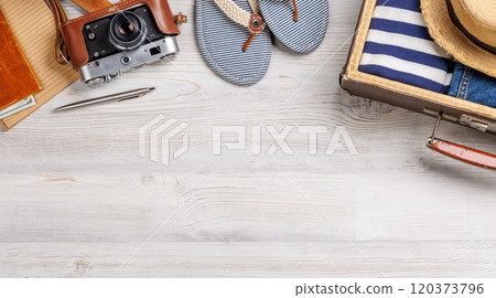 A travel bag with clothes, sun hat, flip flops, and a camera 120373796