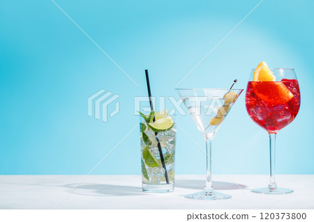 A variety of cocktails arranged on a table against a light blue background 120373800