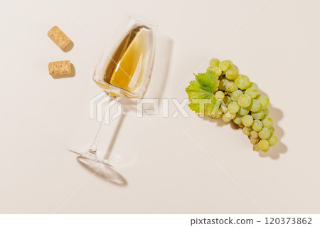 Wine glass alongside grapes and several corks 120373862