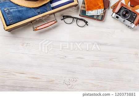 A travel bag with clothes, sun hat, flip flops, and a camera 120373881