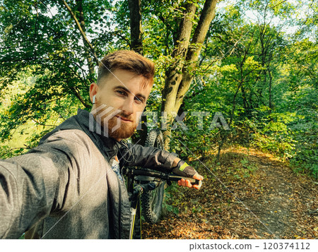 Selfie of a cyclist in the forest. Man smiling while riding his bicycle outdoors. Concept of safety while cycling in the rural areas Selfie of a cyclist in the forest. Man smiling while riding his bicycle outdoors. Concept of safety while cycling in the rural areas 120374112