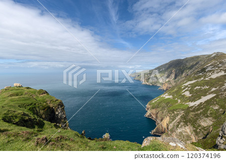 Panoramic view of the Slieve League cliffs in County Donegal, Ireland, with sheep grazing on lush green grass. The expansive Atlantic Ocean stretches into the distance Panoramic view of the Slieve League cliffs in County Donegal, Ireland, with sheep grazing on lush green grass. The expansive Atlantic Ocean stretches into the distance 120374196