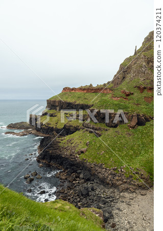 Rugged landscape at Giant's Causeway with basalt columns green grass and dramatic sea  120374211