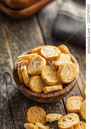 Sliced roasted bruschetta bread in bowl on wooden table. Sliced roasted bruschetta bread in bowl on wooden table. 120374502