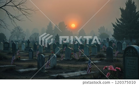 Haunting yet patriotic scene of military cemetery at misty sunset. American flags and flowers adorn countless headstones while a glowing orange sun pierces through foggy evergreens, honoring fallen 120375010