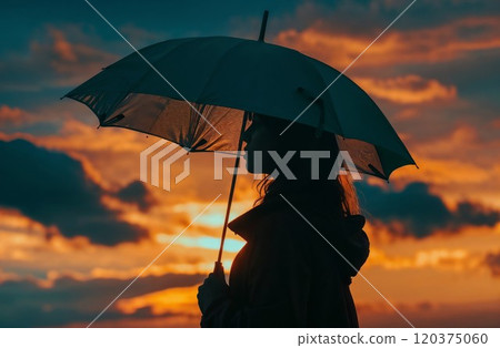 Silhouette of a pregnant woman holding an umbrella against a dramatic orange and teal sunset sky, creating a powerful contrast and peaceful moment 120375060