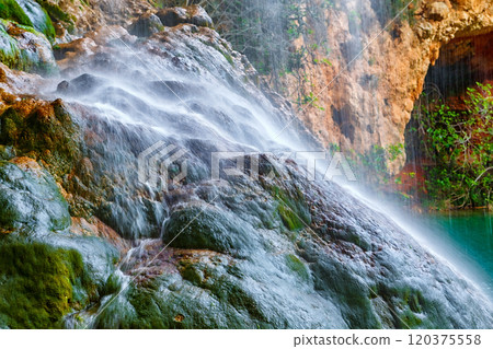 A Tranquil Waterfall Cascading Over Mossy Rocks in a Serene Natural Landscape A Tranquil Waterfall Cascading Over Mossy Rocks in a Serene Natural Landscape 120375558