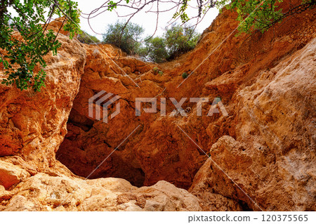 Exploring the Rugged Terrain of a Natural Rock Formation Surrounded by Greenery in Daylight 120375565