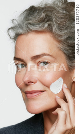 Mature beauty portrait: model applying anti-aging skincare for youthful glow 120375716