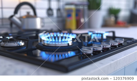 A modern kitchen features a sleek gas stove with blue flames glowing on the burners. Notice the clean countertop and a softly lit background, emphasizing an efficient cooking environment 120376909