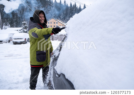Person Clearing Snow from Car in Winter Landscape 120377173