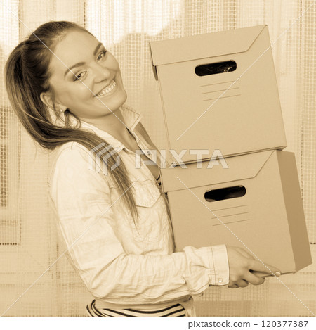 Happy woman moving into house carrying boxes. Happy woman moving into house carrying boxes. 120377387