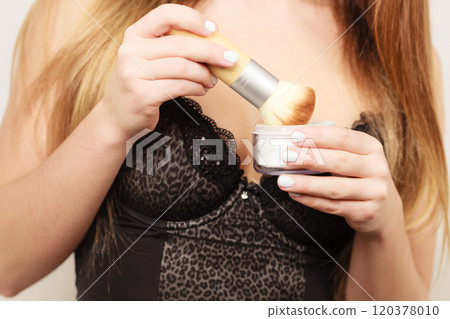 Woman in lingerie applying loose powder with brush 120378010