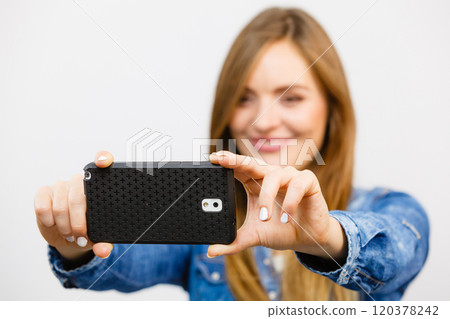 Woman in denim shirt taking self picture with phone Woman in denim shirt taking self picture with phone 120378242