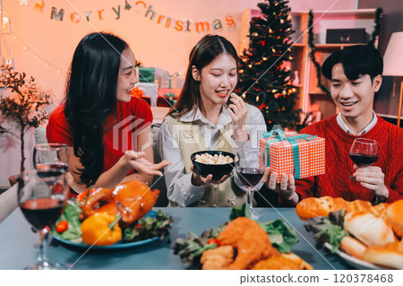 Friends opening Christmas gifts in living room 120378468