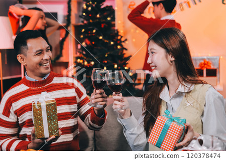 Friends opening Christmas gifts in living room Friends opening Christmas gifts in living room 120378474