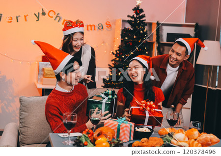 Group of young Asian man and women as friends having fun at a New Year's celebration, holding gift boxes standing by Christmas tree decoration, midnight countdown Party at home with holiday season. Group of young Asian man and women as friends having fun at a New Year's celebration, holding gift boxes standing by Christmas tree decoration, midnight countdown Party at home with holiday season. 120378496