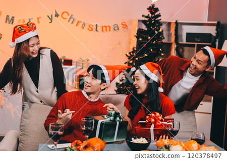 Group of young Asian man and women as friends having fun at a New Year's celebration, holding gift boxes standing by Christmas tree decoration, midnight countdown Party at home with holiday season. Group of young Asian man and women as friends having fun at a New Year's celebration, holding gift boxes standing by Christmas tree decoration, midnight countdown Party at home with holiday season. 120378497