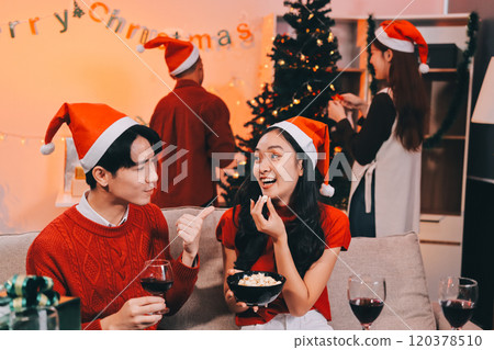 Group of young Asian man and women as friends having fun at a New Year's celebration, holding gift boxes standing by Christmas tree decoration, midnight countdown Party at home with holiday season. 120378510