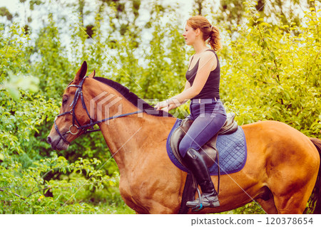 Young woman ridding on a horse 120378654