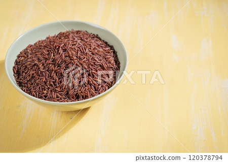 A bowl of red raw rice is placed on a yellow table A bowl of red raw rice is placed on a yellow table 120378794